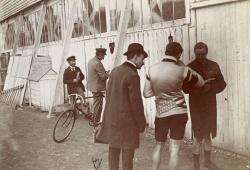 deux gardiens ouvrent la porte d’un bâtiment de bois blanc, pour y ranger une bicyclette de course